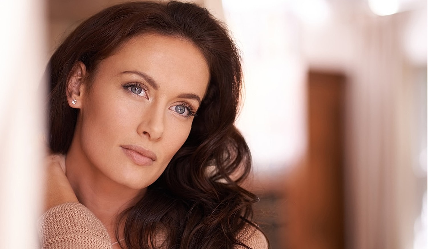Woman with long hair posing thoughtfully indoors.